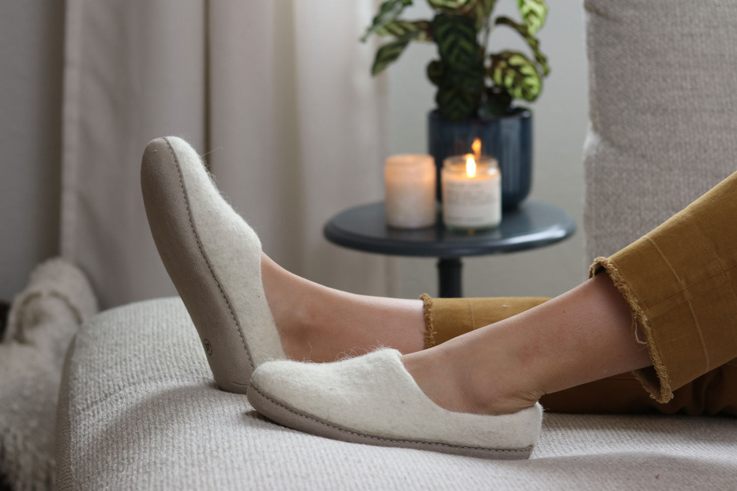 Woman laying on couch wearing Nootkas Victoria wool sliippers in Oatmeal