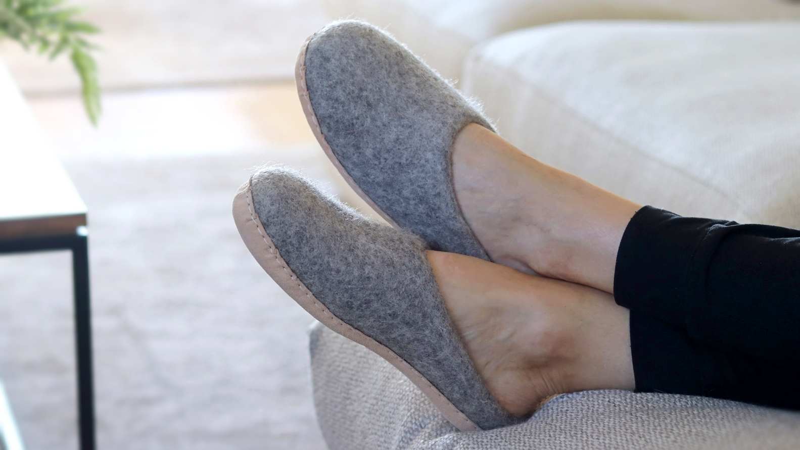 women on couch wearing nootkas wool slippers in heather