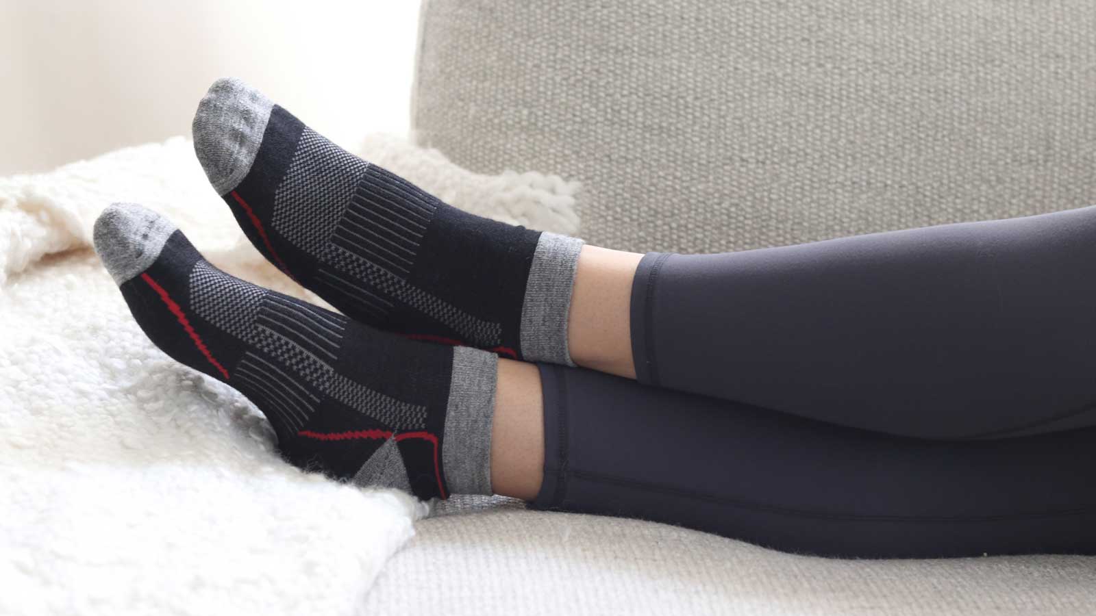 Women laying on couch with Nootkas Alpaca Sports socks in black